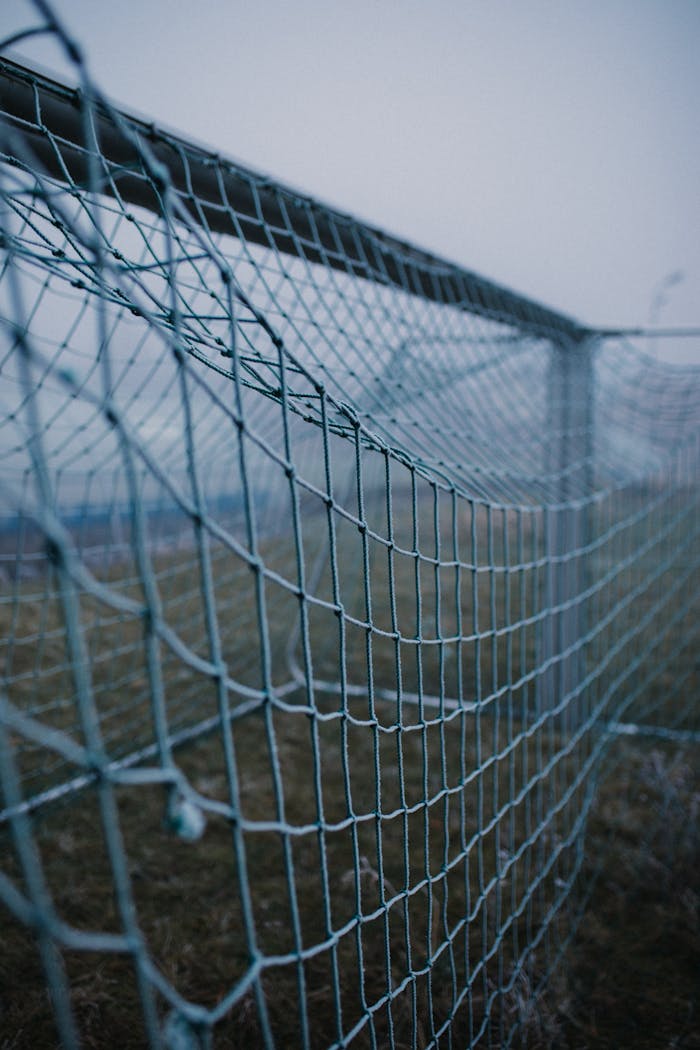 Crafting Captivating Headlines: Your awesome post title goes here Detailed close-up of an empty football goal net under overcast, gloomy sky, capturing the essence of anticipation in a football field.